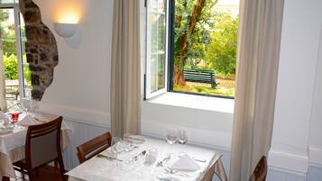 A dining area with a table set for four, a stone accent wall, and a view of a garden with a bench.