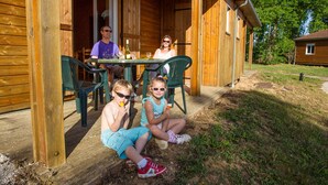 A wooden cabin with a porch, outdoor seating, and a grassy yard. - Domaine de la Vingeanne (Villegusien-le-Lac)