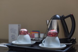 Deux théières blanches, dotées de couvercles rayés de rouge et de blanc, sont posées sur un plateau noir.