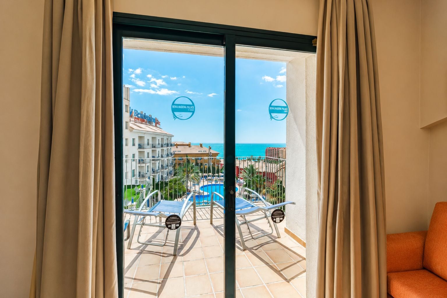 A hotel room with a view of a pool, beach, and ocean.