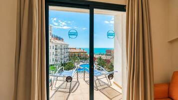 A hotel room with a view of a pool, beach, and ocean.