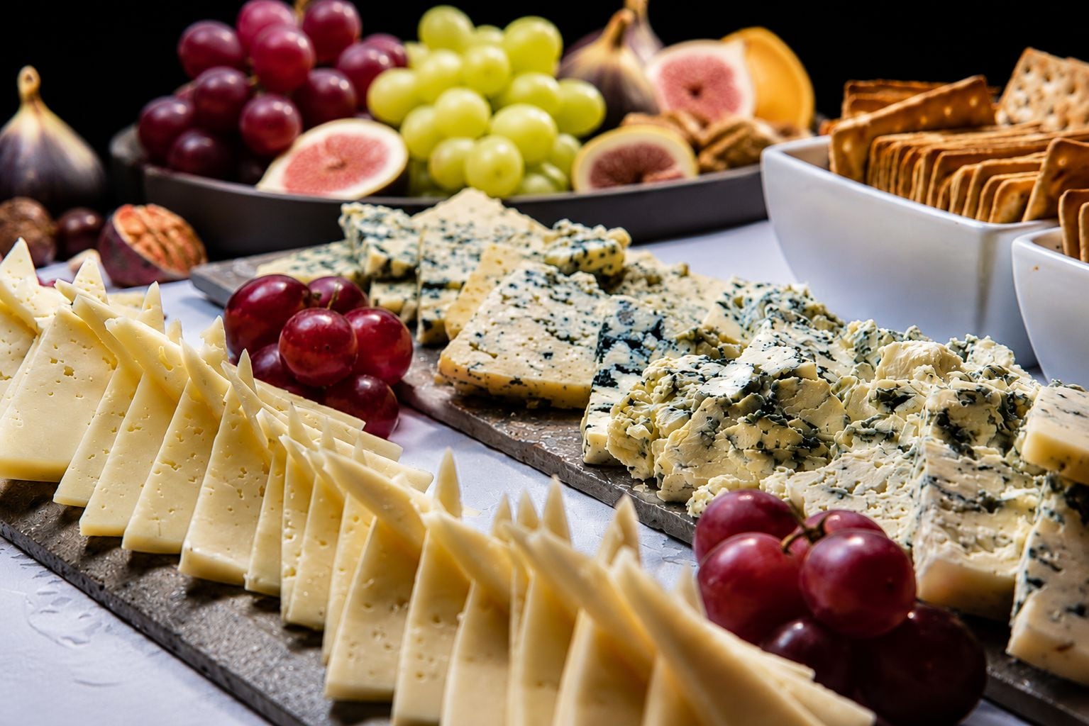 A variety of cheeses and fruits on a board.