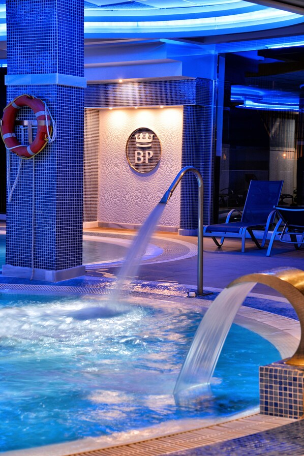 A pool area with a water feature, lounge chairs, and a life ring. - Benalmádena Palace - Hotel SPA & Apartments (Benalmádena)