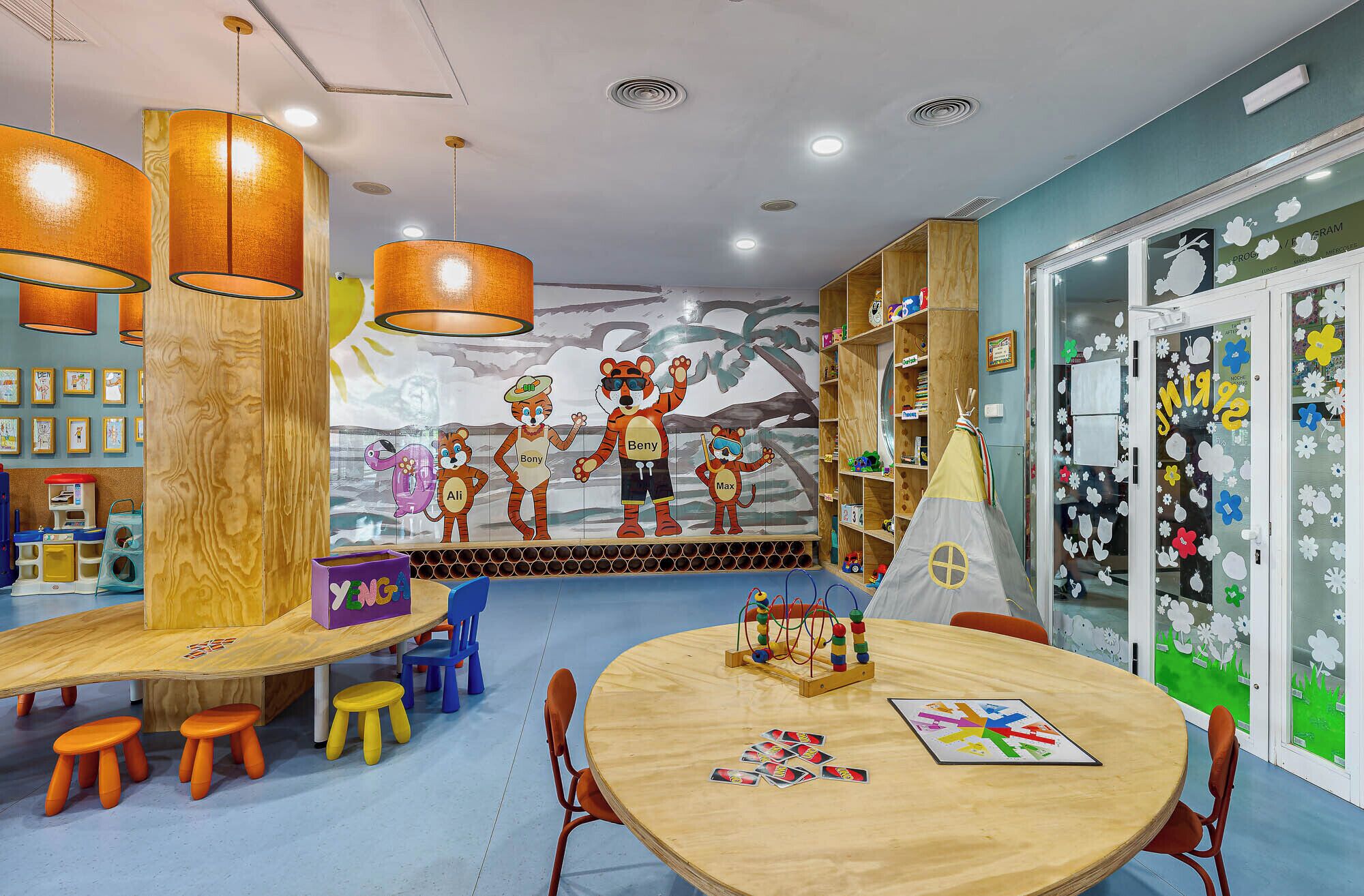 Un salón infantil con muebles de madera, un mural y juguetes educativos.