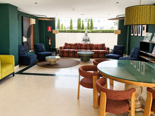 A modern lounge area with a sofa, chairs, a round table, and a statue.
