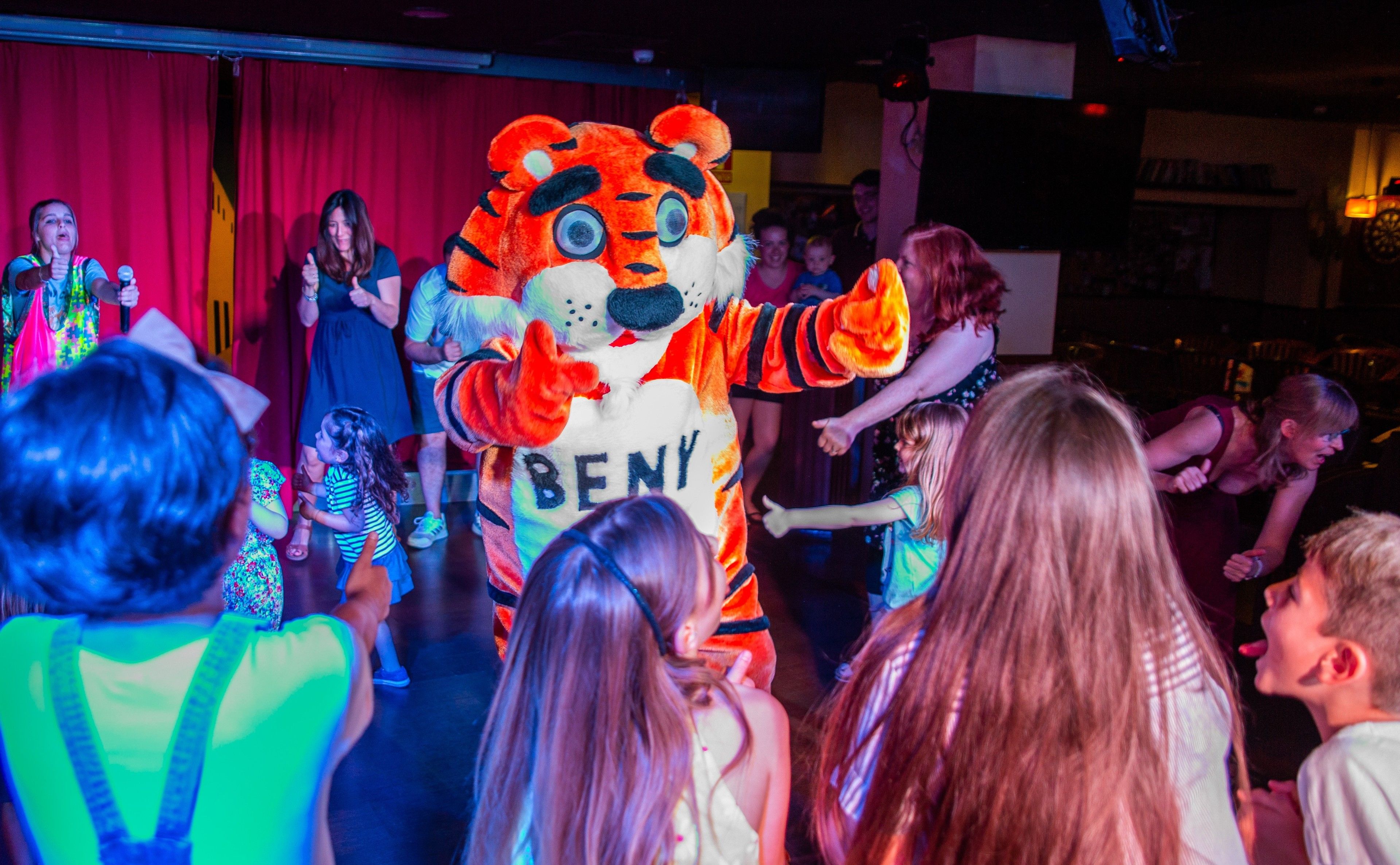 A tiger mascot interacting with children on a stage.