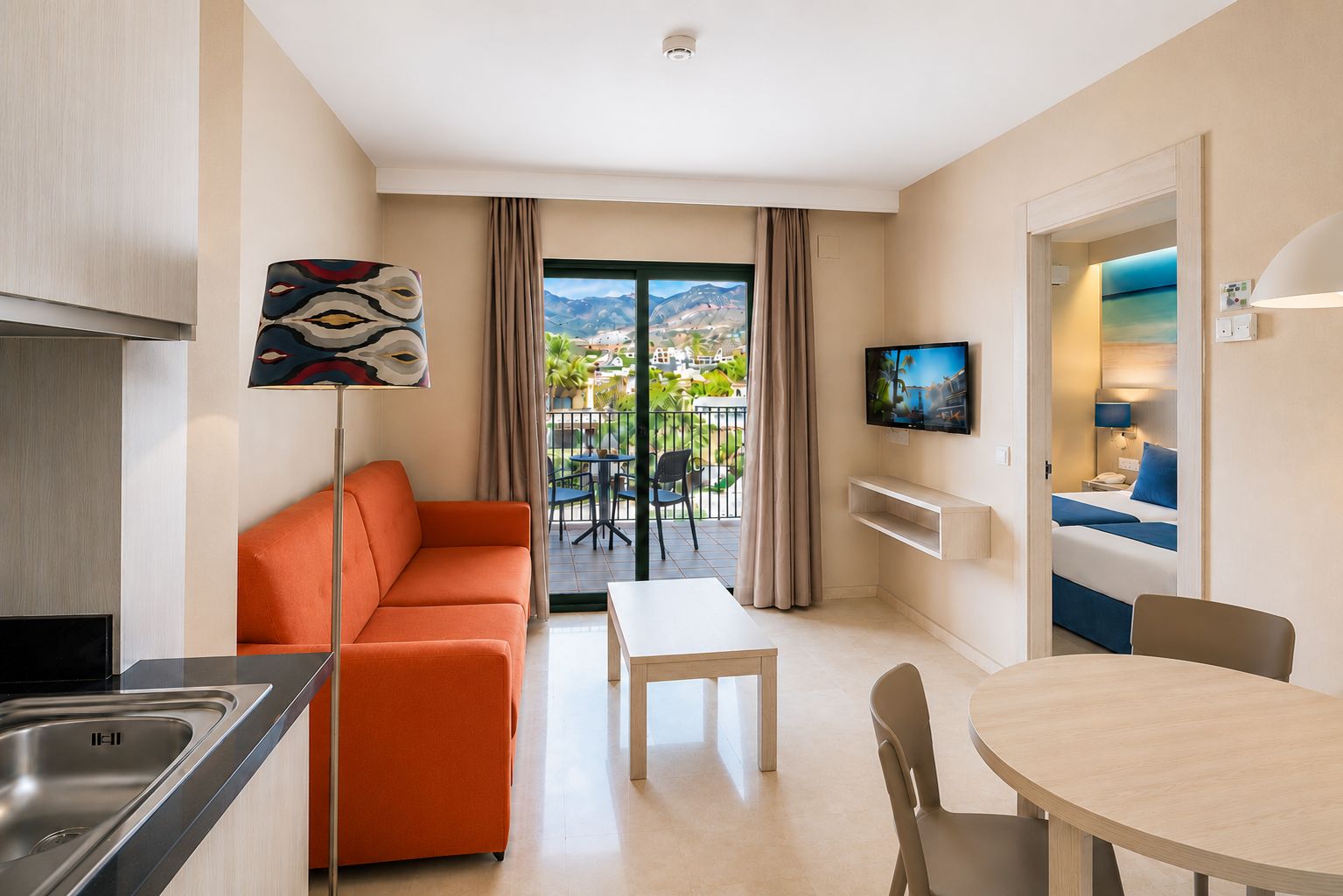 Une chambre d’hôtel moderne équipée d’un canapé, d’une table à manger, d’une télévision et d’un balcon avec vue.