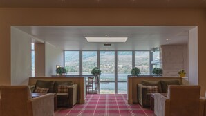 Une pièce spacieuse avec un tapis à carreaux rouges, deux canapés et une vue sur un lac, visible à travers de grandes fenêtres.
