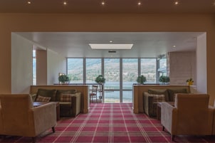 A spacious room with a red plaid carpet, two sofas, and a view of a lake through large windows.