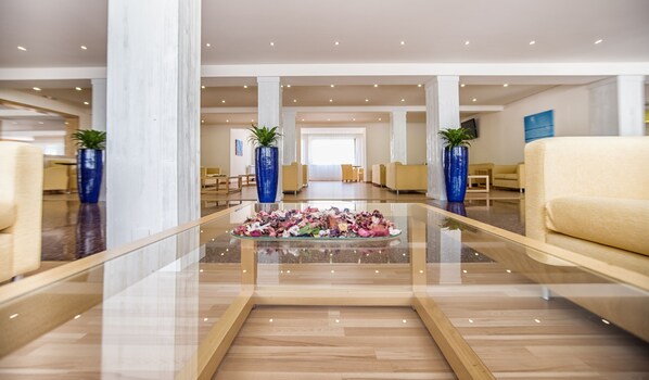 Un hall d’entrée spacieux, doté d’une table basse en verre sur laquelle est disposée une composition florale, d’un parquet en bois et d’espaces de détente au design moderne.