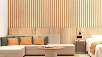 Una habitación de hotel moderna con sofá modular, una mesita de centro redonda, una mesita de noche con lámpara y un cabecero de madera.