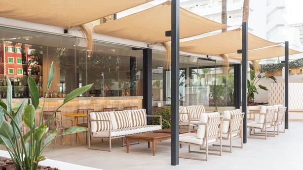 An outdoor seating area with cushioned sofas and chairs, a wooden coffee table, and large umbrellas providing shade. - Tangerine by Honne Hotels - Adults Only ¨New Opennig¨ (Calvia)