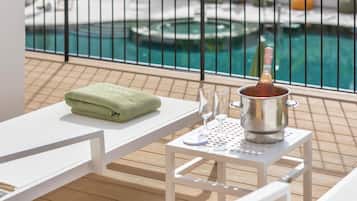 A poolside area with a white table, a green towel, and a champagne bucket.