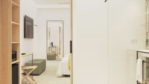 A modern hotel room with a minimalist design, featuring a flat-screen TV, a small table, a green sofa, and a large mirror. - Tangerine by Honne Hotels - Adults Only ¨New Opennig¨ (Calvia)