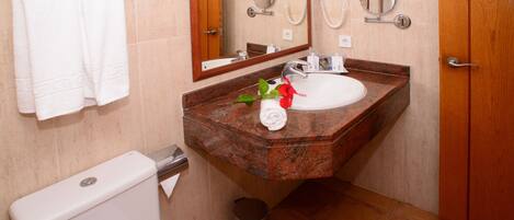 Un baño con lavabo de mármol, un inodoro, un cubo de basura y una puerta de madera.