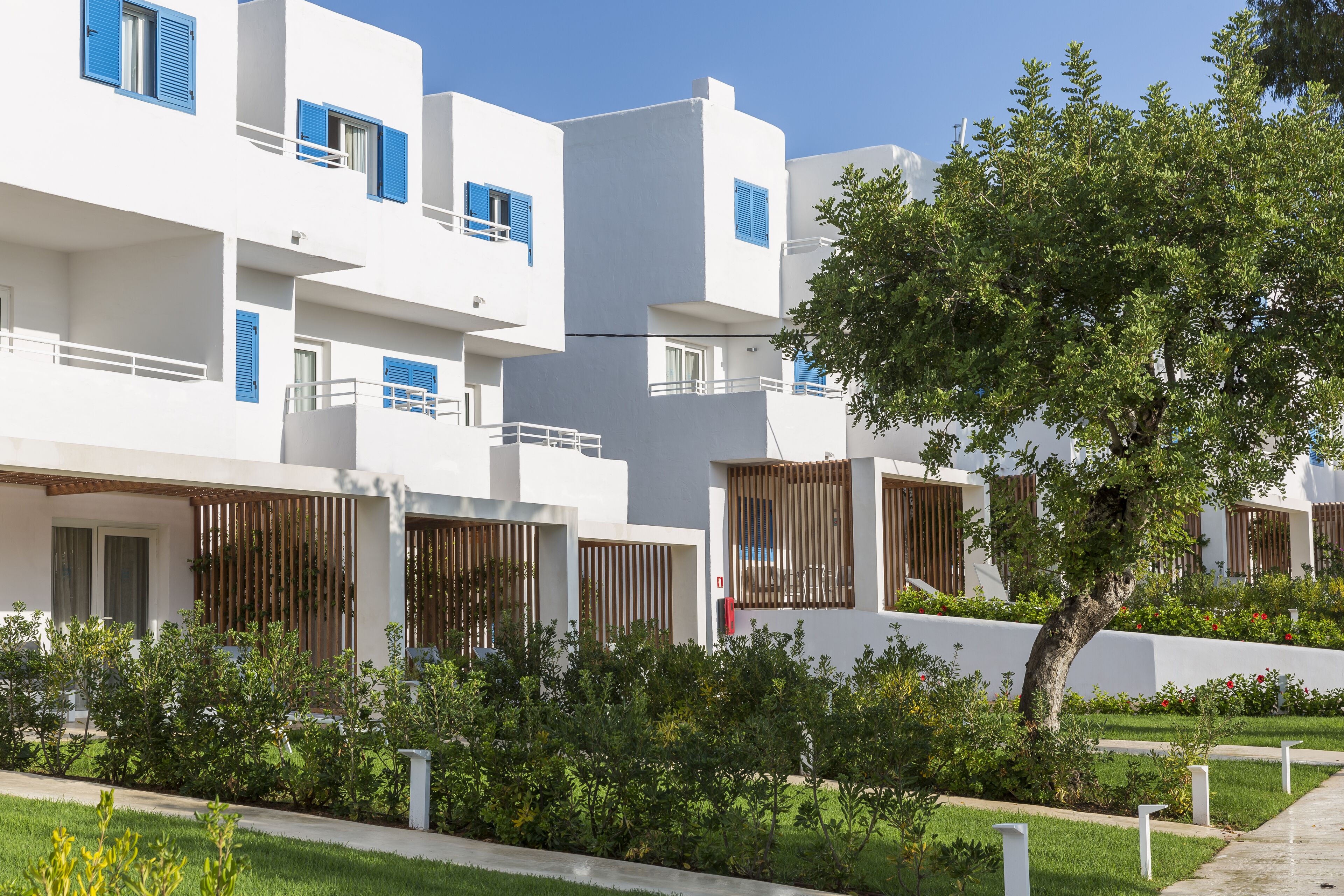 Un bâtiment moderne aux murs extérieurs blancs, aux volets bleus et doté de balcons.