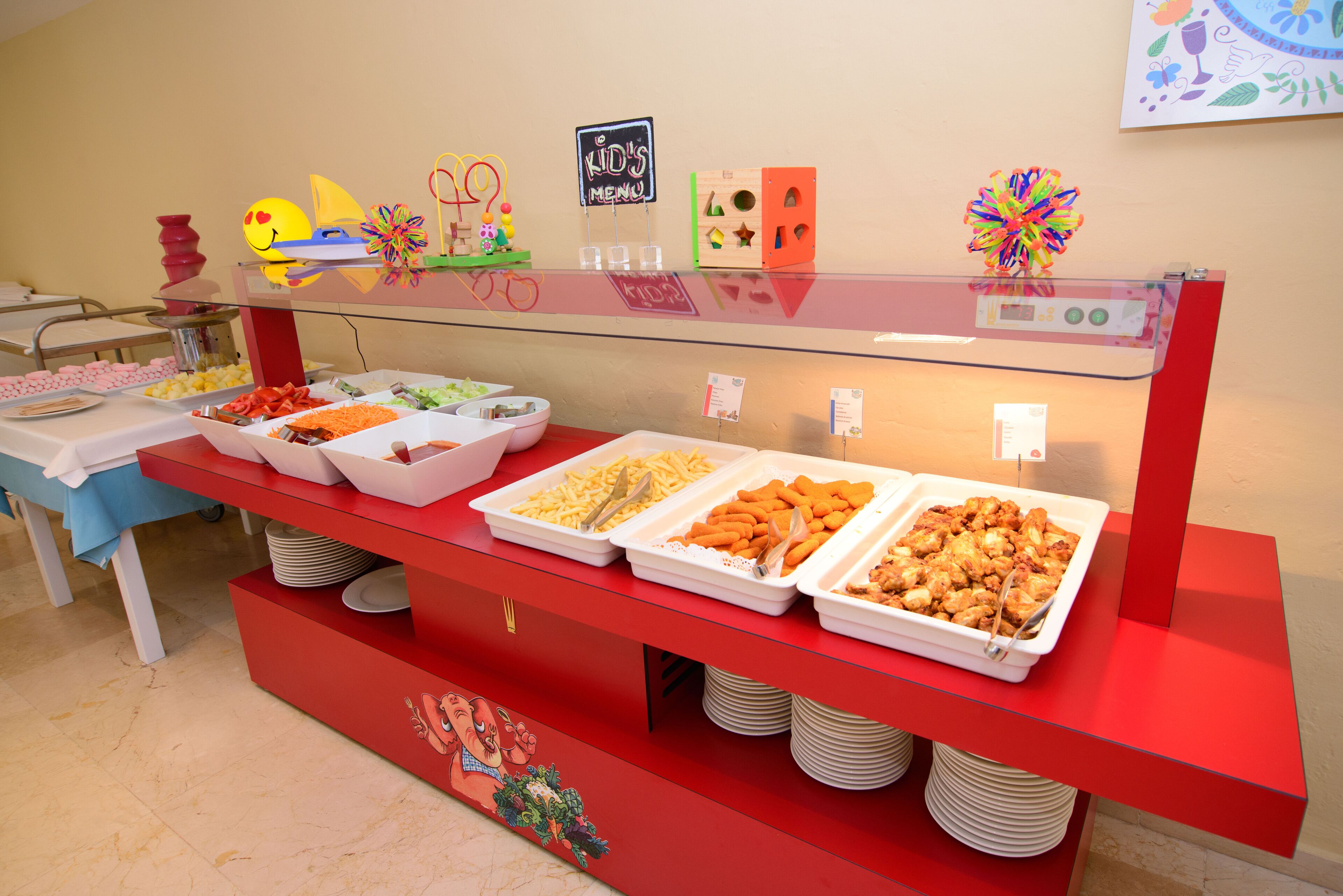 Un bufé con diversas opciones de comida y un letrero del menú infantil.