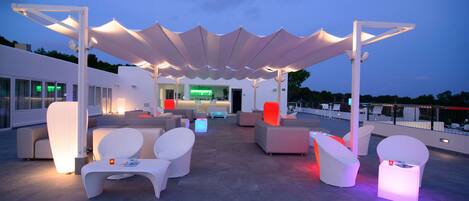 A rooftop lounge area with modern seating and a covered section.