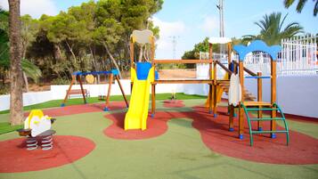 Un parque infantil con tobogán, columpios y estructuras para escalar.