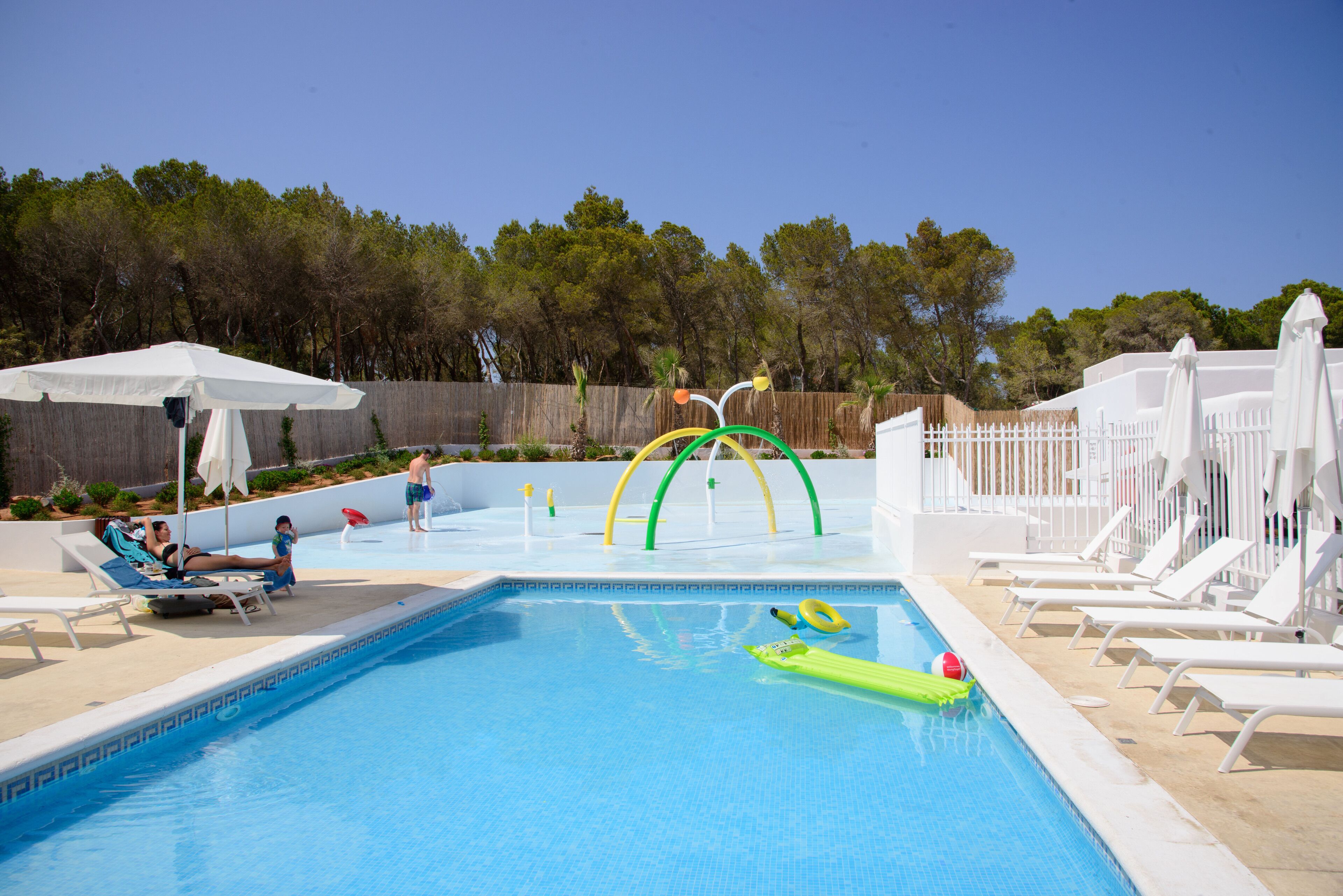 Uma piscina com espreguiçadeiras e um parquinho.