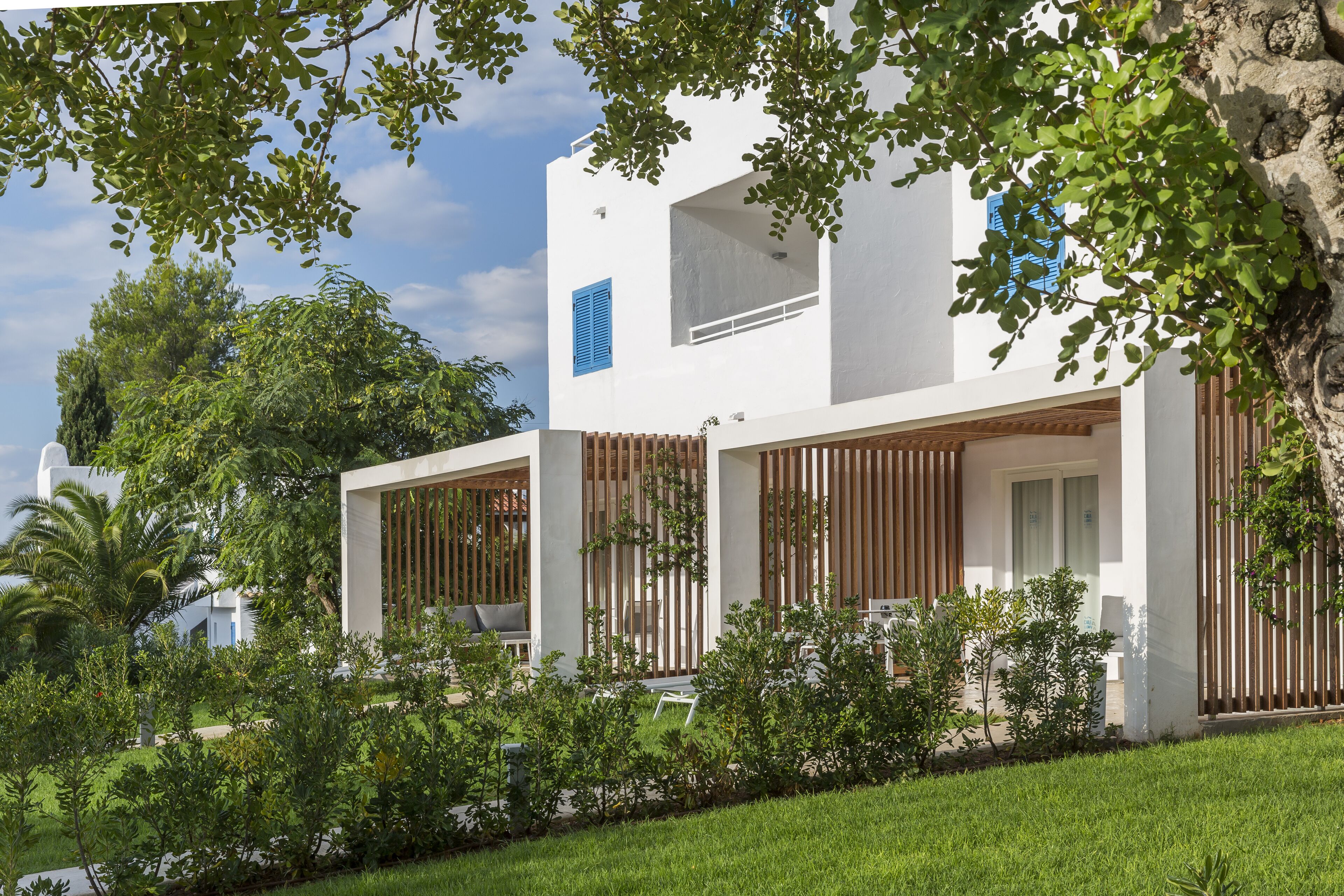 Une maison moderne à deux étages, avec une façade blanche, de grandes fenêtres et un jardin bien entretenu.