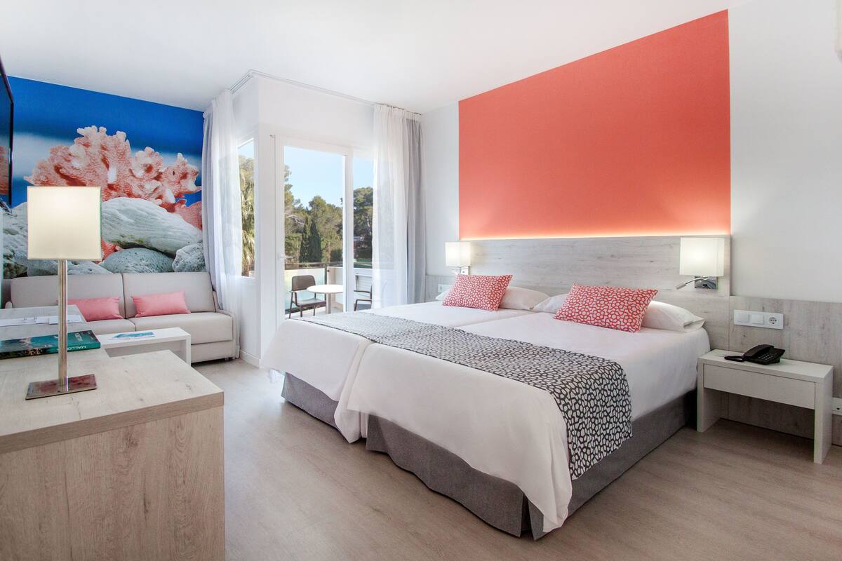 Une chambre d’hôtel moderne avec un grand lit, un bureau avec une lampe, un canapé et un tableau au mur.