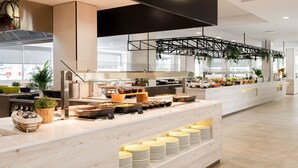 A modern kitchen area with a buffet setup, including various food stations and a seating area with tables and chairs. - Globales Hotel Maioris (Llucmajor)