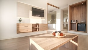 A modern kitchen with wooden cabinetry, a built-in TV, and a dining area with a wooden table. - Globales Hotel Maioris (Llucmajor)