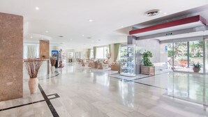 A spacious lobby with a marble floor, a reception desk, comfortable seating areas, and a glass display case. - Globales Hotel Maioris (Llucmajor)