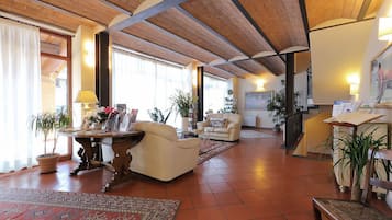 Un'ampia zona giorno con soffitto in legno a vista, una grande finestra e un accogliente camino.