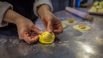 Hands shaping dough on a stainless steel surface.