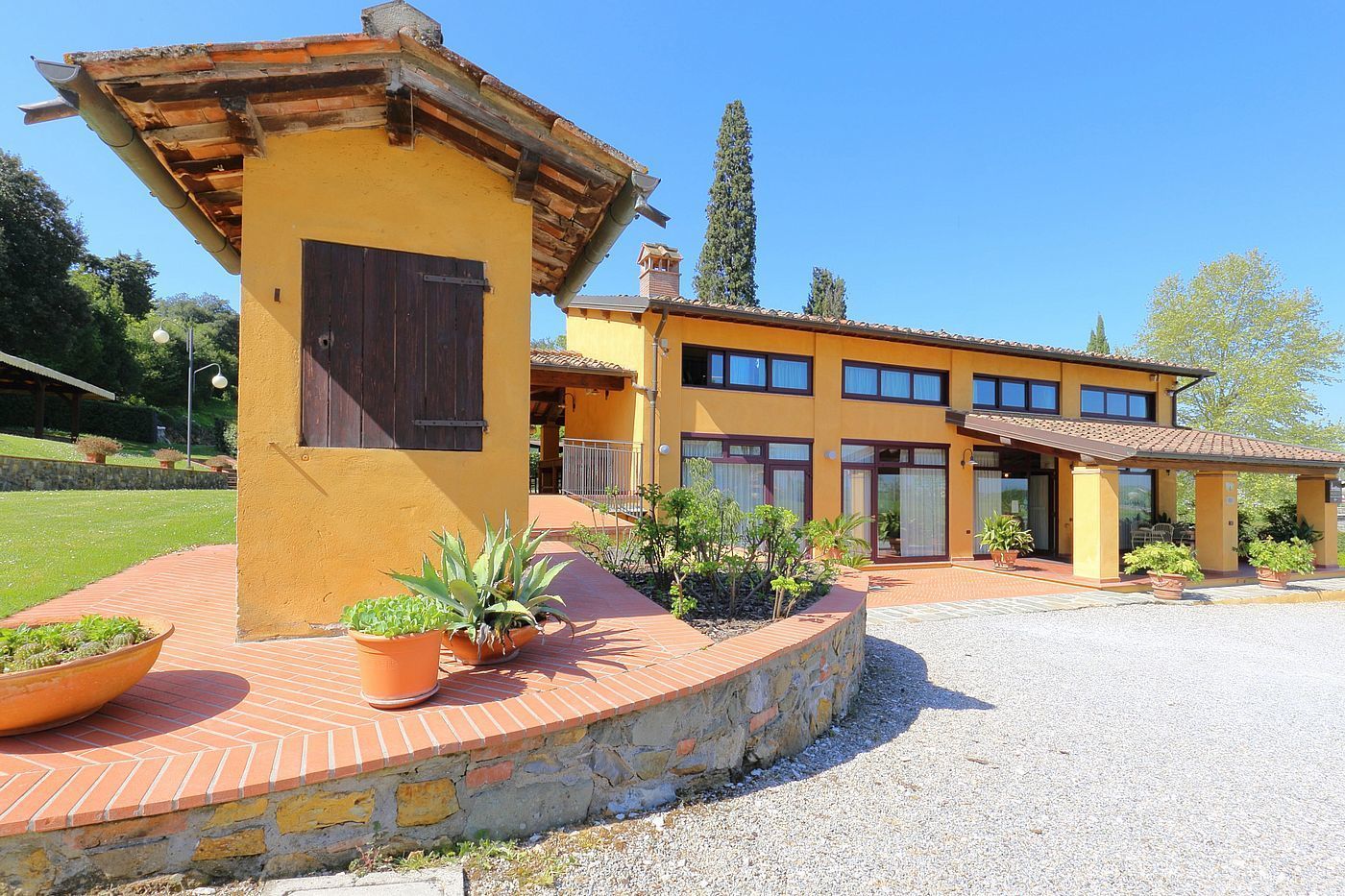 A yellow building with a stone foundation, large windows, and a covered patio area.