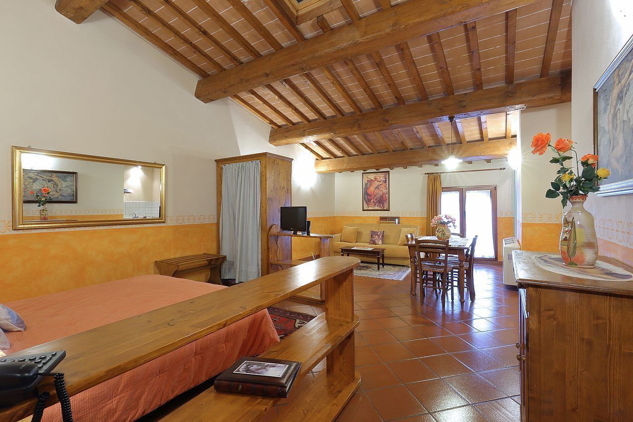 A room with a wooden bed, a wooden bench, a television, a sofa, and a dining table.