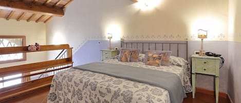 A bedroom with a large bed, two bedside tables, a wooden ceiling, and a window with a view.