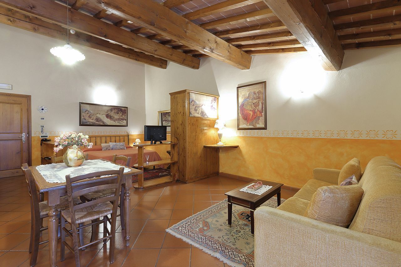A cozy living room with a wooden ceiling, a dining area with a table and chairs, and a sofa.
