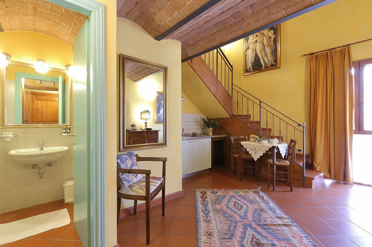 A spacious kitchen with a dining area, a staircase, and a bathroom with a sink and mirror.