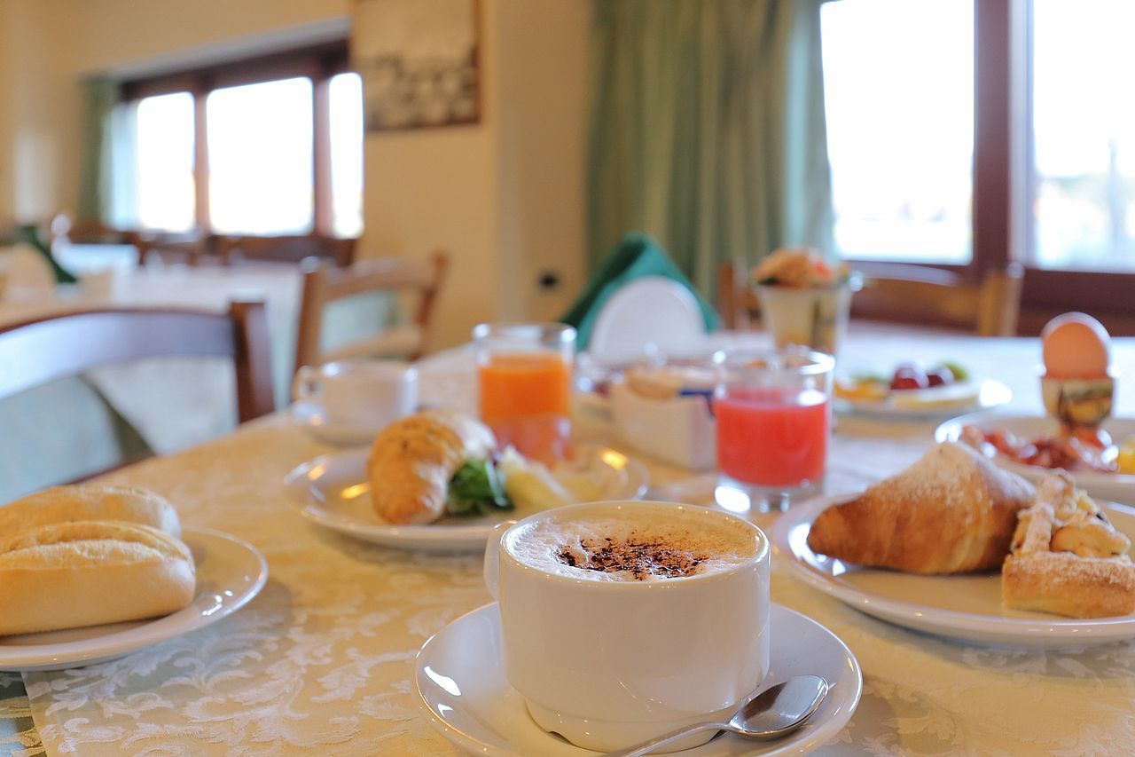 A breakfast setting with croissants, a cup of coffee, and a glass of orange juice on a table.