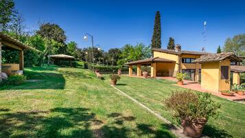Zona residenziale con prato curato, un gazebo e una fila di case gialle con tetti in tegole.