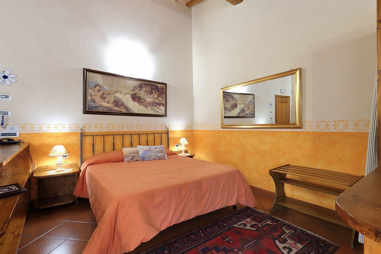 Une chambre à coucher avec un lit, des tables de chevet, un miroir et des œuvres d’art accrochées aux murs.