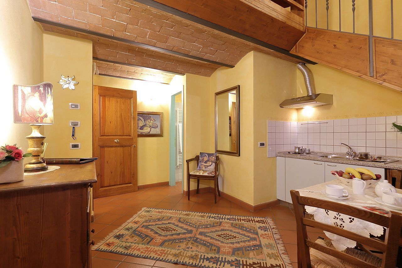 Una cocina con mostrador de madera, un lavamanos y una zona de comedor con una mesa preparada para dos.