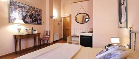 A hotel room with a bed, bedside table, lamp, and a painting on the wall.