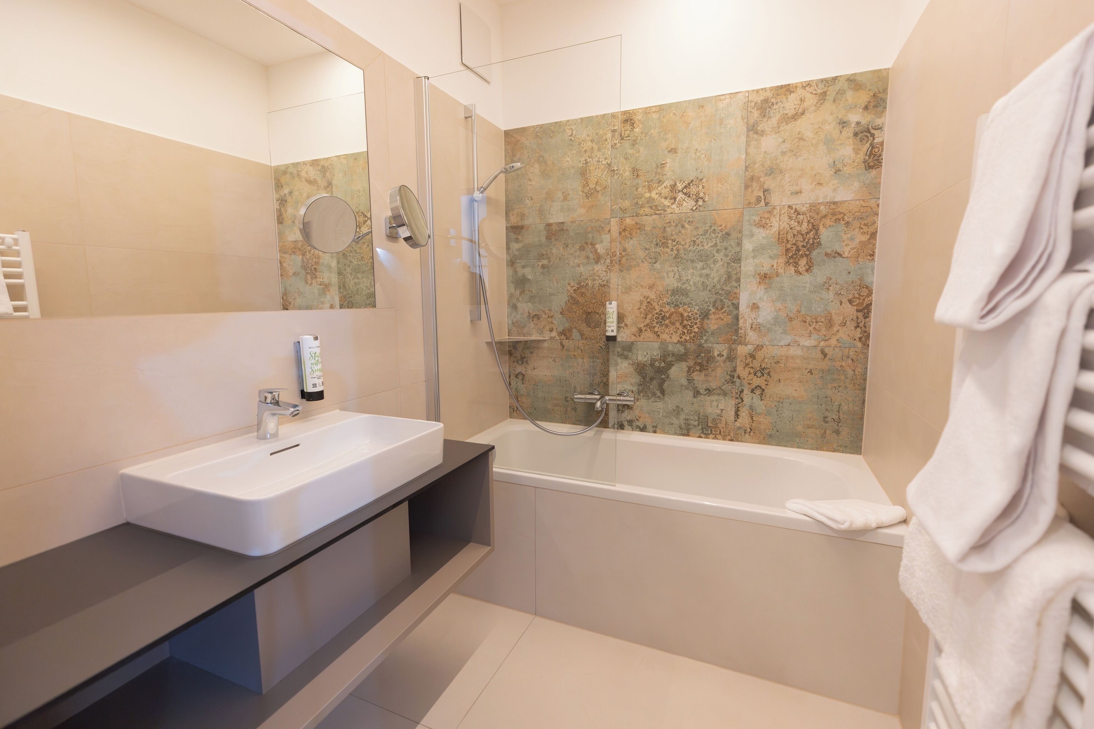 A modern bathroom with a white sink, a bathtub, and a shower area.