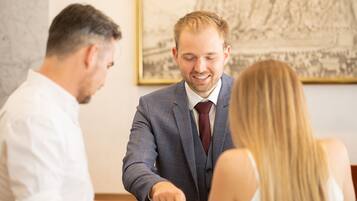 Un hombre con traje sentado a una mesa con otras dos personas.