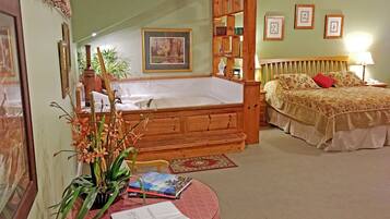 A bedroom with a large bed, a wooden headboard, a nightstand, a lamp, a bookshelf, and a window with a view of a house.