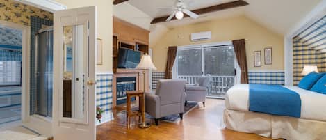 A bedroom with a bed, a chair, a small table, and a fireplace.