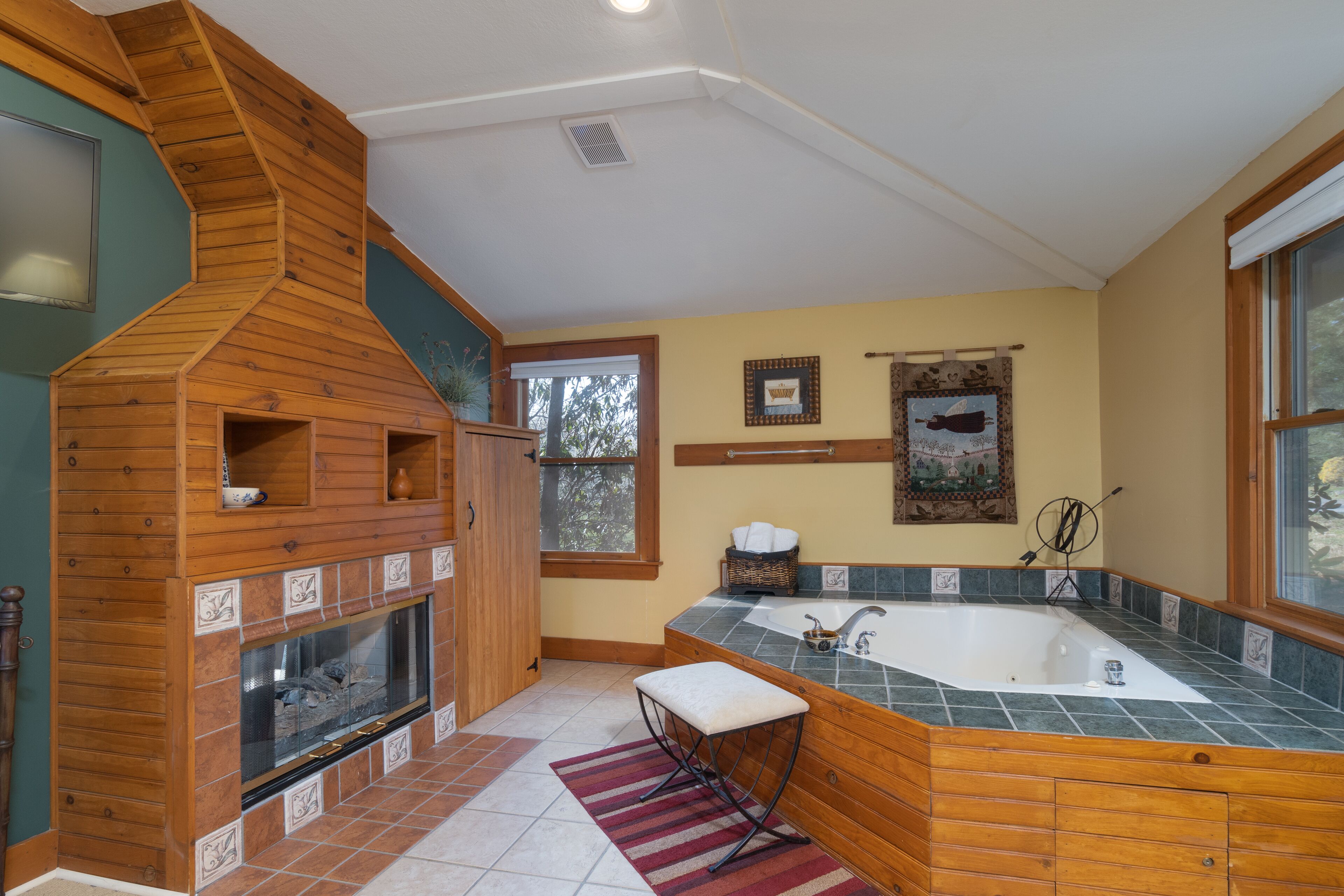 Une salle de bain avec un meuble-lavabo en bois, une grande baignoire et une cheminée.