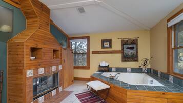 A bathroom with a wooden vanity, a large bathtub, and a fireplace.