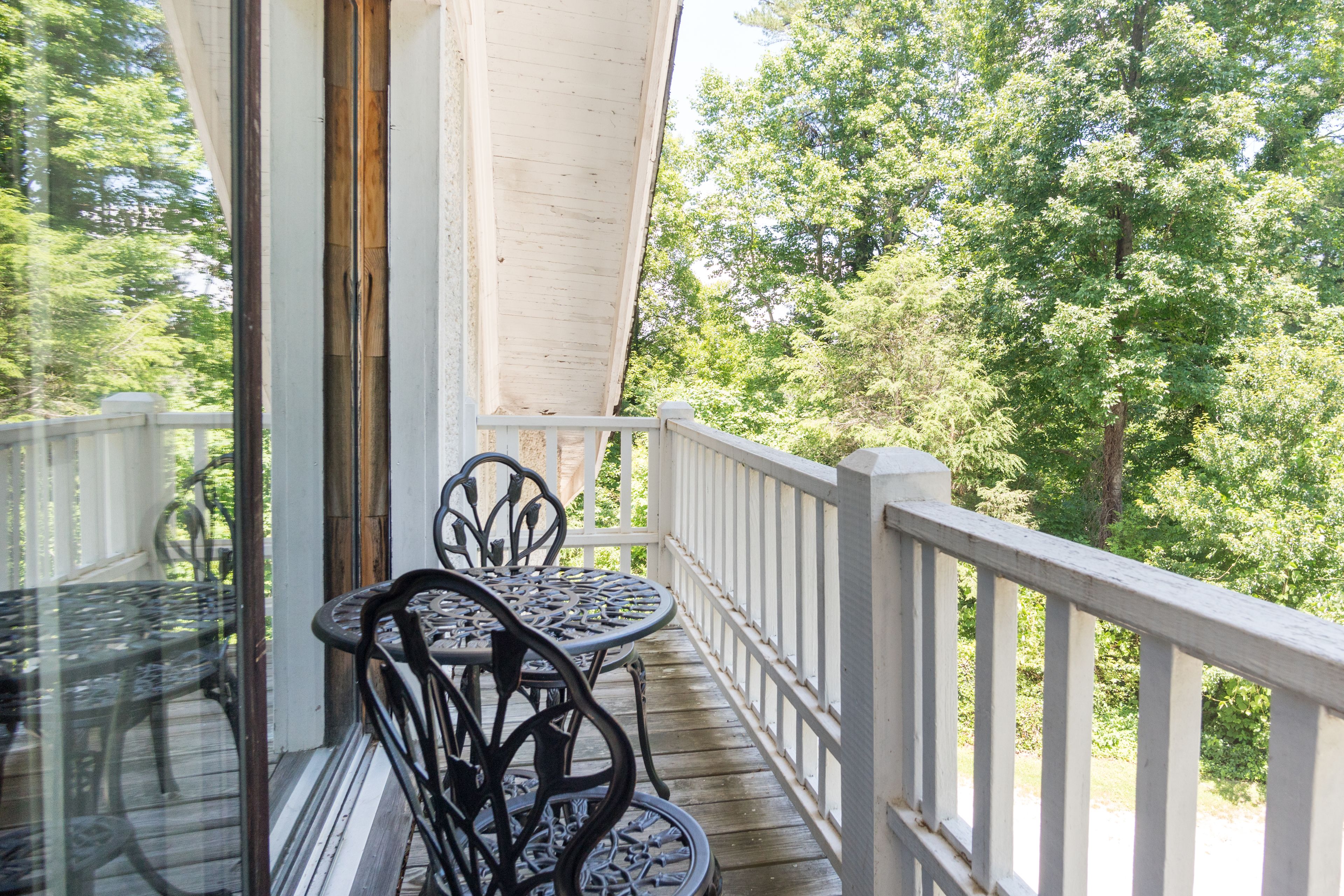 A wooden deck with a white railing, a glass door, and a table with chairs.