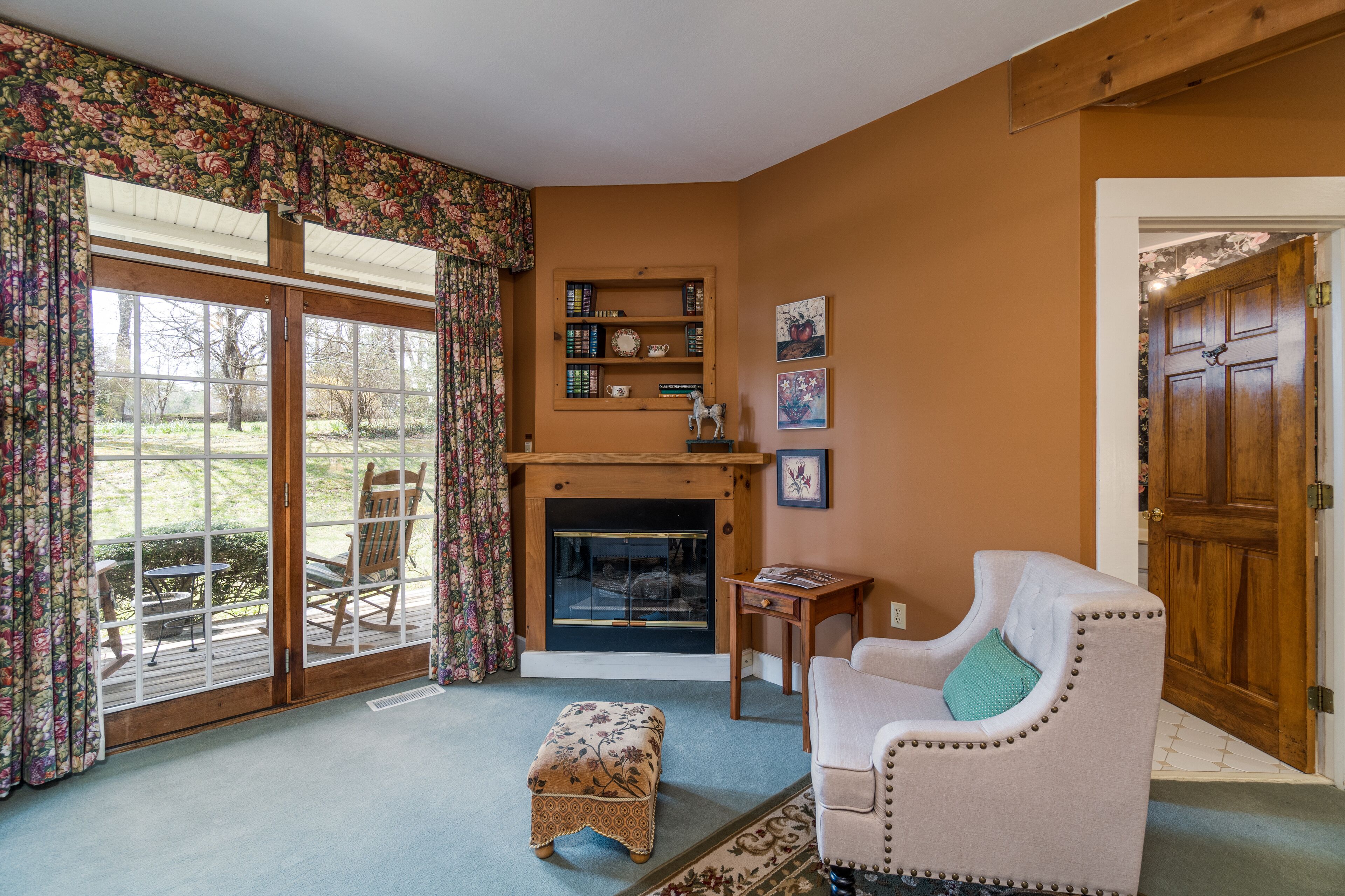A living room with a fireplace, a bookshelf, a sofa, and a dining area with chairs.