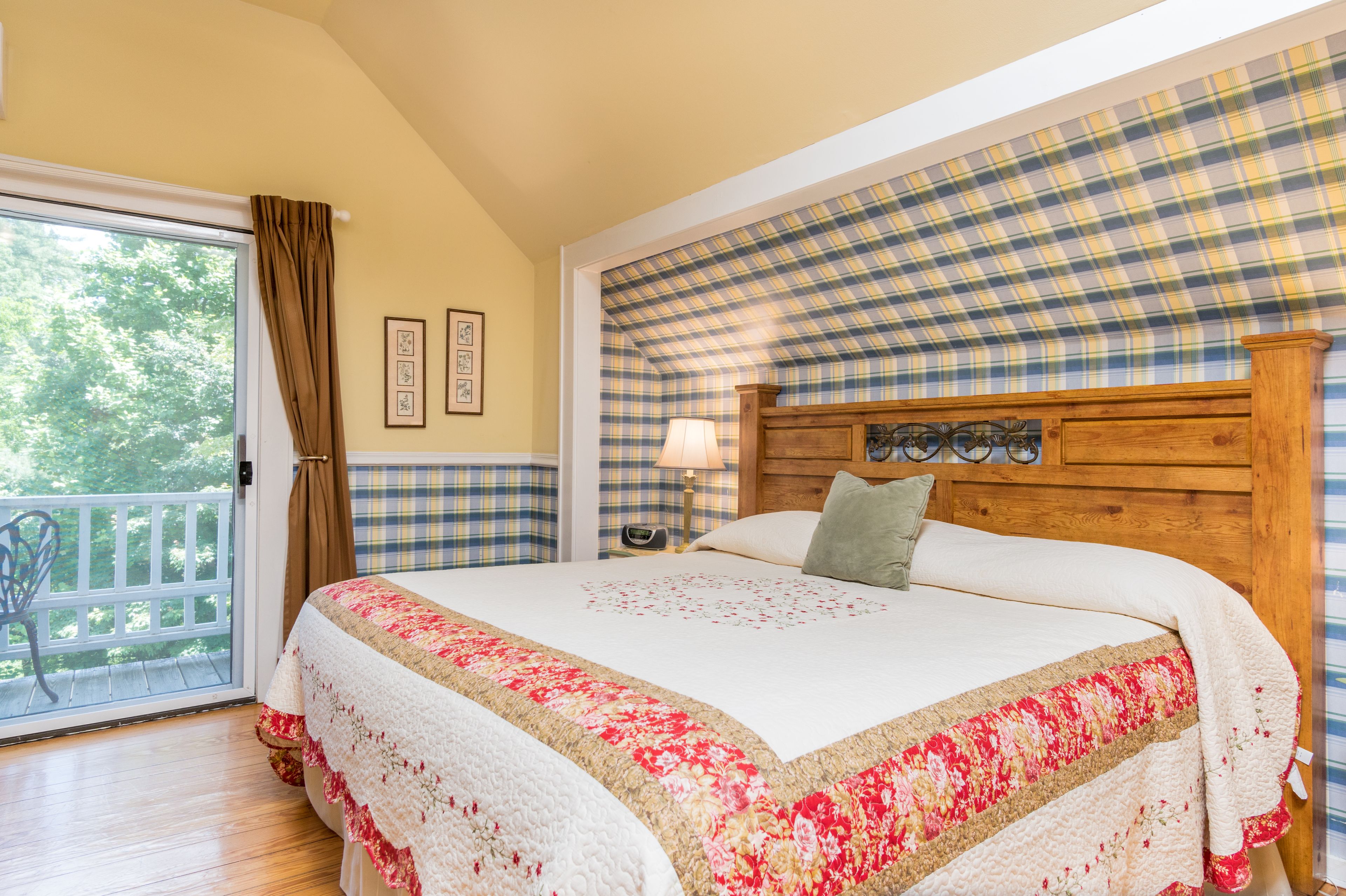 Una camera da letto con un letto grande, una testiera in legno, un comodino, una lampada e vista sull'esterno tramite una porta scorrevole.